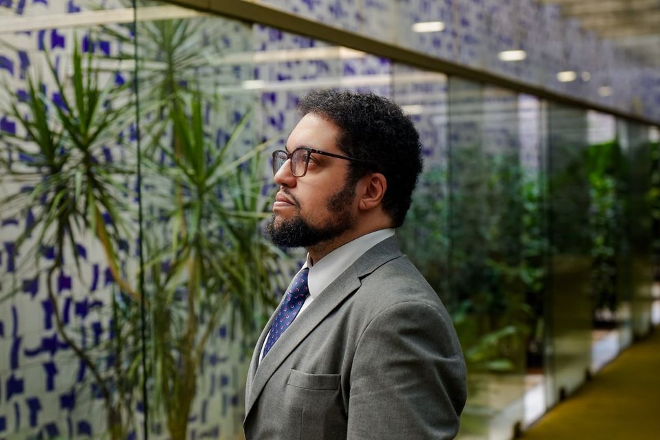 Rodrigo Corrêa, advogado, de perfil, diante de um painel de azulejos azuis e brancos